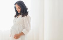 A pregnant woman standing in her house